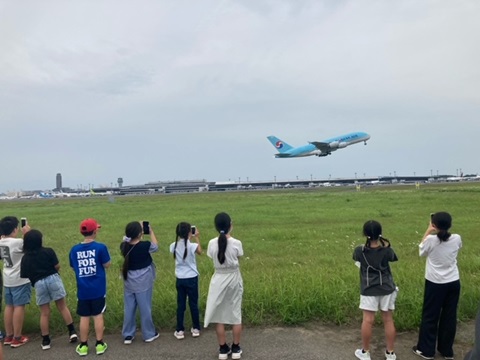 A滑走路で飛行機を見学する子どもたちの画像