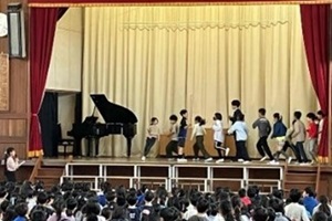 児童が舞台上で長縄8の字連続跳びを披露する写真