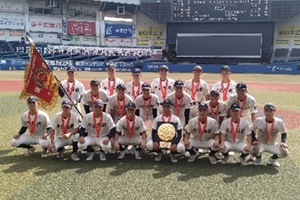 メダルを首にかけ優勝旗と盾とともに映る記念写真