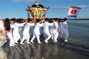 神輿を担いて海の中へ向かう担ぎ手たちの写真