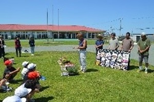 屋外で講師の説明を受ける児童の写真