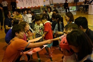 幼稚部の幼児が選手に手作りの金メダルと似顔絵を手渡している写真